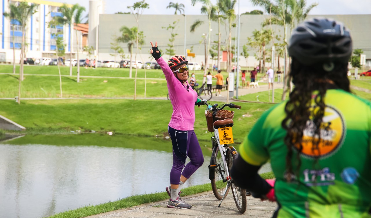 mulher fazendo sinal da vitória ao lado da sua bicicleta